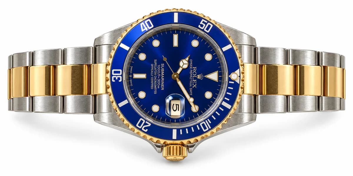 Blue-dial two-tone Rolex Submariner arranged horizontally on white