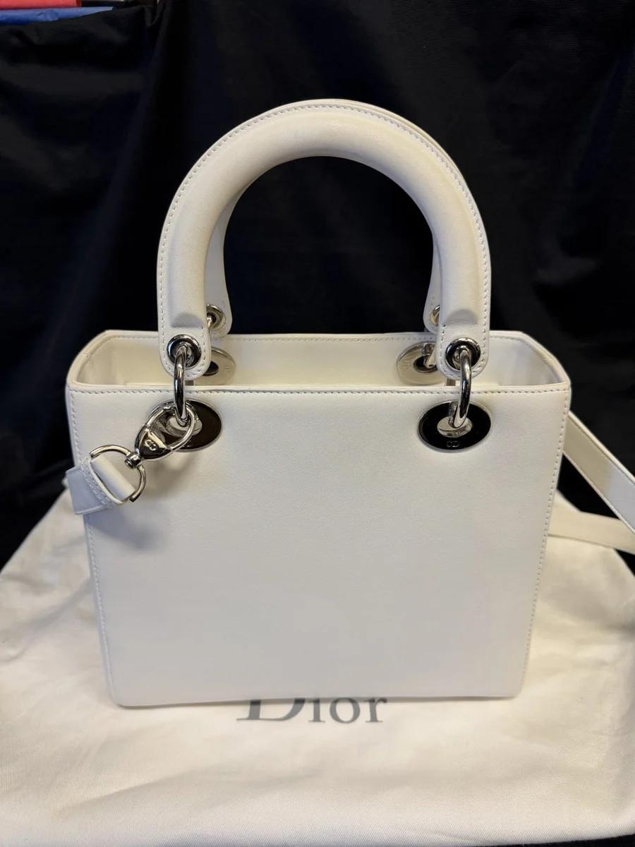 Close-up of a Christian Dior Medium Lady Dior handbag in white calfskin with Cannage quilting and the hanging D.I.O.R. charms, bought and authenticated by San Diego Jewelry Buyers